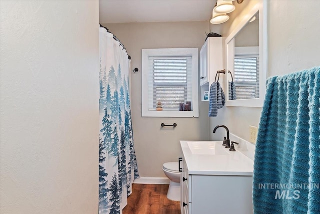 bathroom featuring baseboards, toilet, a shower with shower curtain, wood finished floors, and vanity