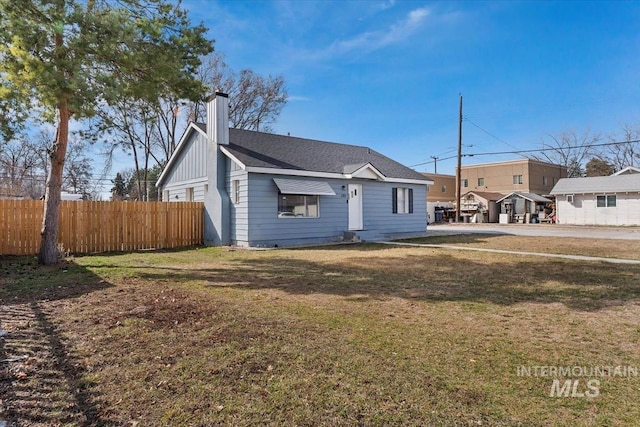 exterior space featuring a yard, fence, board and batten siding, and a chimney