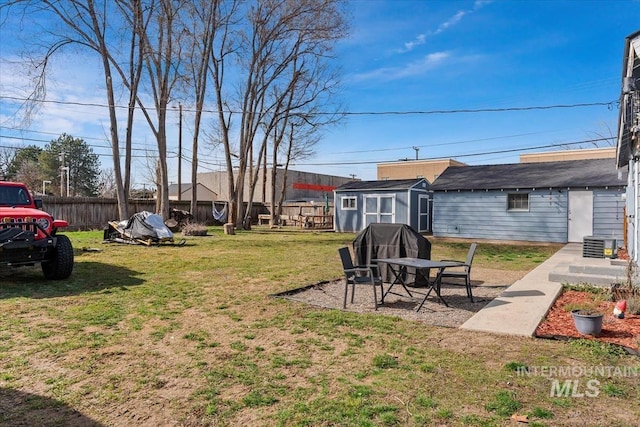 view of yard featuring entry steps, fence, cooling unit, a storage shed, and an outdoor structure