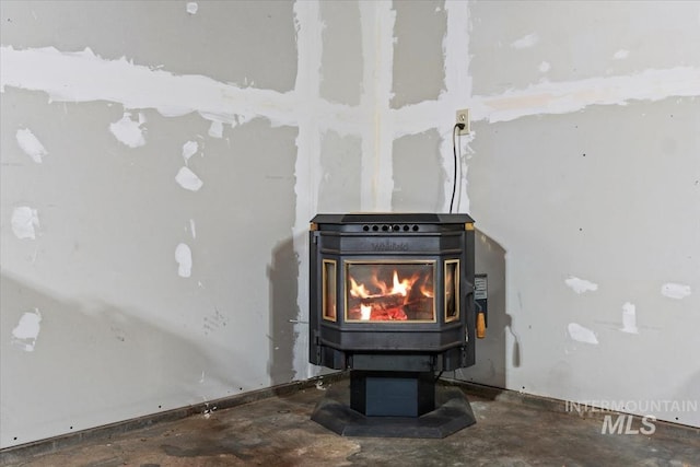 details featuring unfinished concrete floors and a wood stove