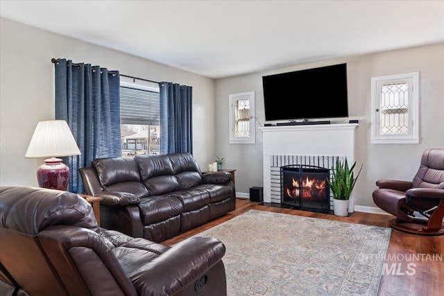 living room featuring a fireplace with flush hearth, wood finished floors, and baseboards