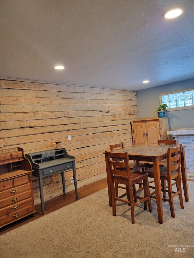 dining area featuring wooden walls, carpet floors, and a textured ceiling