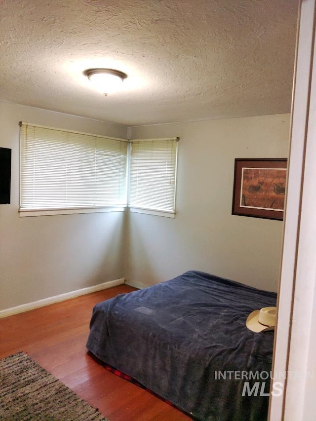 bedroom featuring a textured ceiling and wood-type flooring