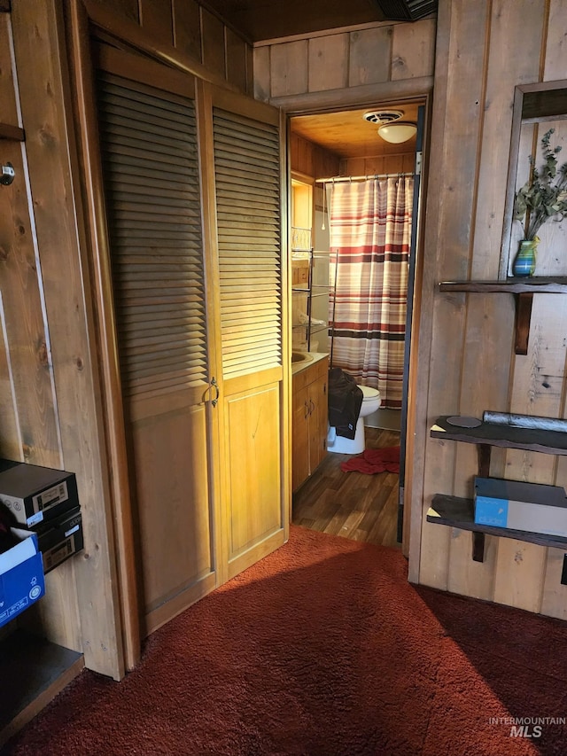 hallway with dark colored carpet and wooden walls