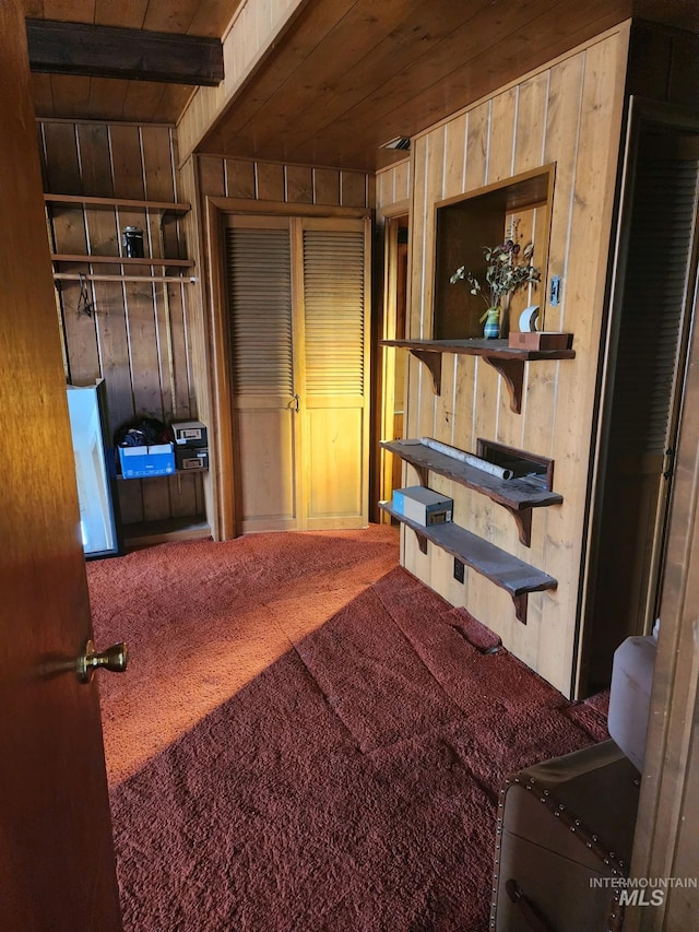 bedroom with beam ceiling, wood ceiling, carpet, and wooden walls