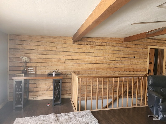 interior space with ceiling fan, beam ceiling, dark hardwood / wood-style floors, wood walls, and a textured ceiling