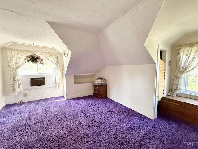 bonus room featuring lofted ceiling, baseboards, carpet, and an AC wall unit