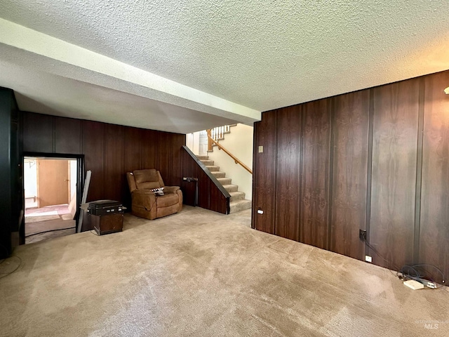 finished below grade area with wooden walls, carpet floors, stairs, and a textured ceiling
