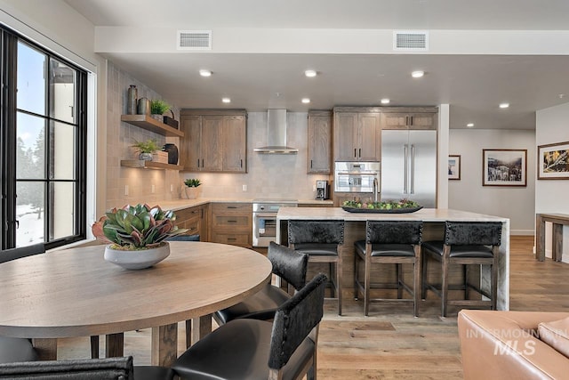 kitchen featuring a kitchen island, appliances with stainless steel finishes, plenty of natural light, and wall chimney range hood