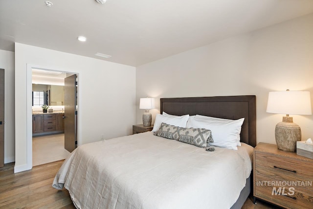 bedroom with hardwood / wood-style flooring and connected bathroom