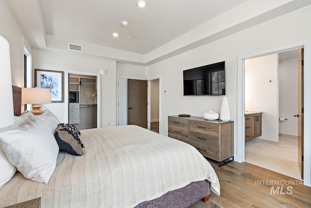 bedroom featuring ensuite bathroom, light hardwood / wood-style floors, and a closet