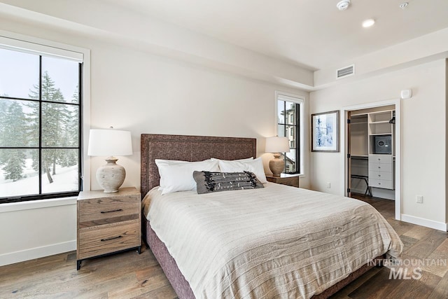 bedroom with dark hardwood / wood-style floors and multiple windows