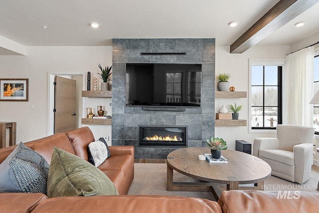 living room featuring beamed ceiling and a tiled fireplace