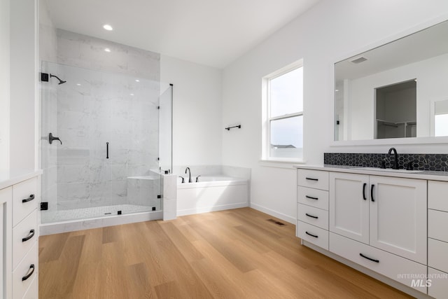 bathroom featuring plus walk in shower, vanity, and hardwood / wood-style flooring