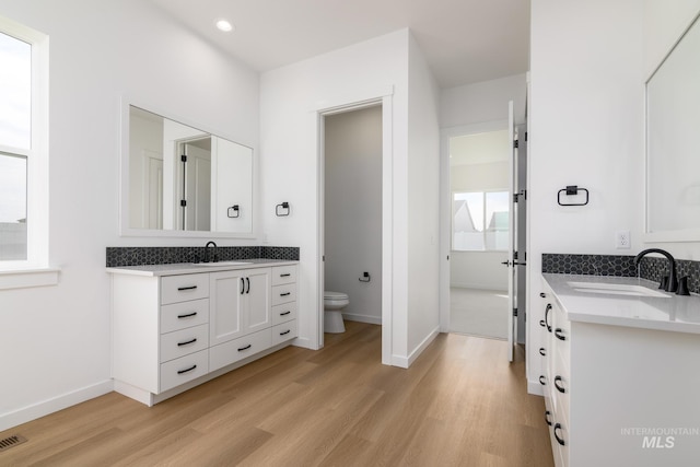 bathroom featuring hardwood / wood-style floors, vanity, toilet, and decorative backsplash