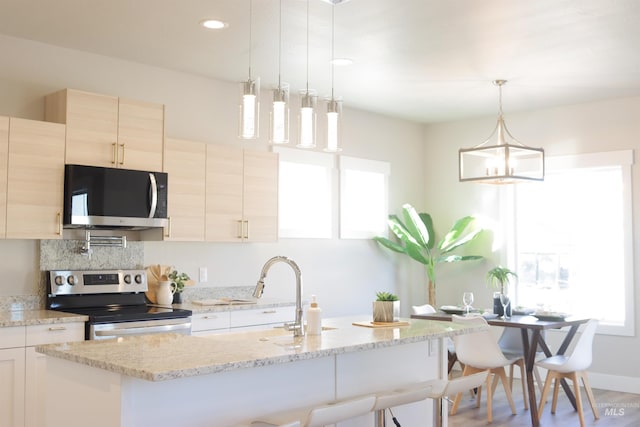 kitchen with a kitchen breakfast bar, light stone counters, pendant lighting, and stainless steel appliances