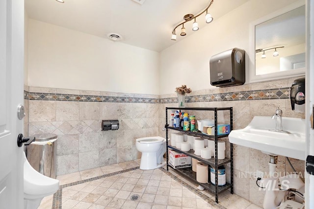 201 W A St, Vale, OR 97918 - bathroom with tile walls, wainscoting, tile patterned floors, rail lighting, and inlaid floor details