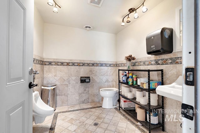 201 W A St, Vale, OR 97918 - bathroom with tile walls, a wainscoted wall, tile patterned floors, rail lighting, and inlaid floor details
