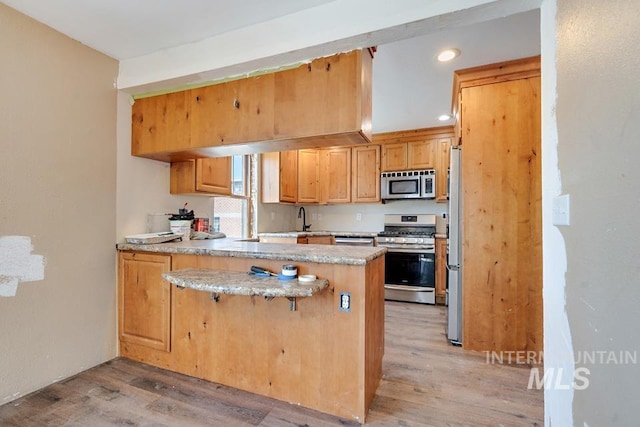 201 W A St, Vale, OR 97918 - kitchen with stainless steel appliances, a peninsula, light wood finished floors, recessed lighting, and a kitchen bar