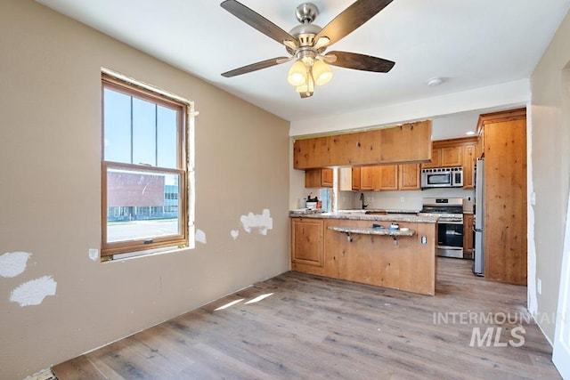 201 W A St, Vale, OR 97918 - kitchen with appliances with stainless steel finishes, a peninsula, light wood-style floors, and ceiling fan