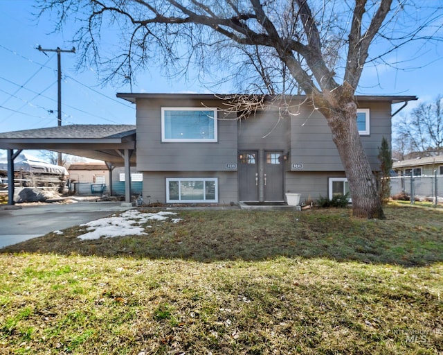 back of house with driveway, fence, an attached carport, and a yard