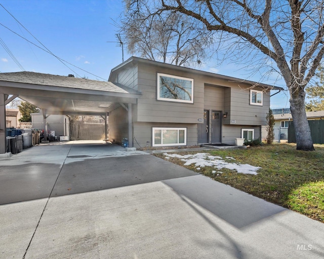 bi-level home featuring concrete driveway, a carport, and fence