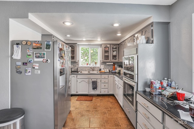 kitchen featuring gray cabinetry, decorative backsplash, sink, and appliances with stainless steel finishes