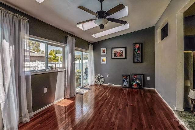 interior space featuring hardwood / wood-style floors, ceiling fan, and vaulted ceiling with skylight