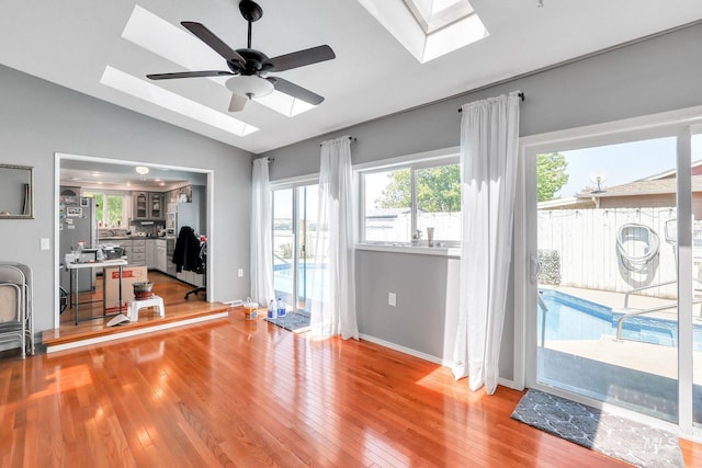 interior space featuring hardwood / wood-style flooring, lofted ceiling with skylight, and ceiling fan