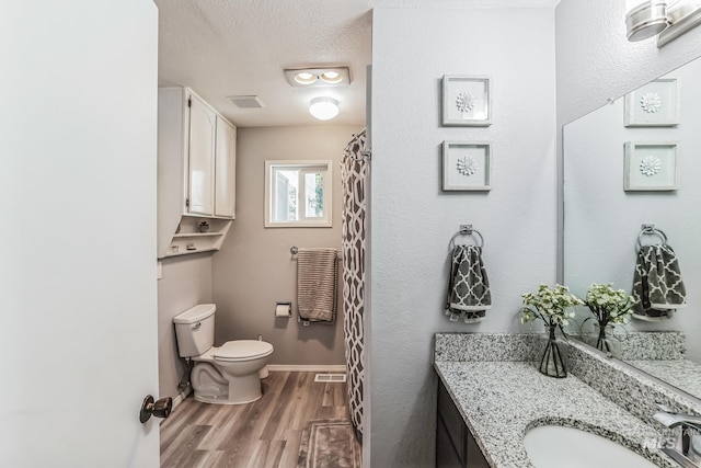 bathroom featuring a textured ceiling, vanity, hardwood / wood-style flooring, and toilet