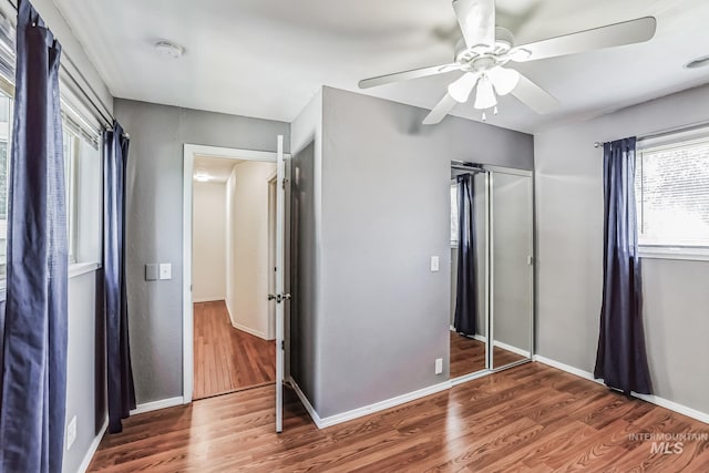 unfurnished bedroom with ceiling fan, a closet, and dark wood-type flooring