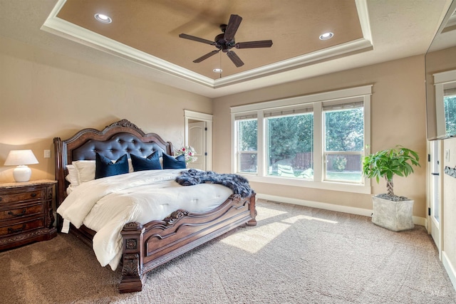 bedroom with ceiling fan, carpet floors, and a tray ceiling