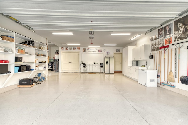 garage featuring fridge, stainless steel fridge, and a garage door opener