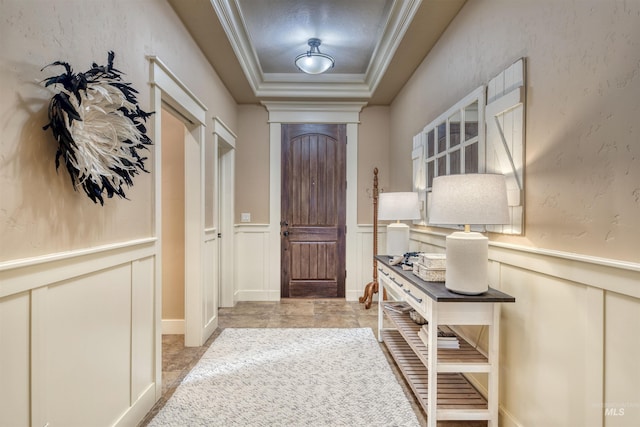 doorway to outside featuring ornamental molding and a tray ceiling