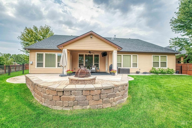 rear view of house with a patio, ceiling fan, an outdoor fire pit, and a yard