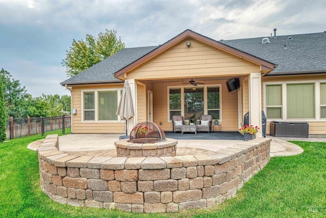 back of property with ceiling fan, an outdoor fire pit, a lawn, and a patio