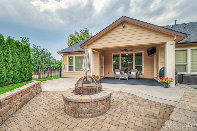 rear view of house with ceiling fan, a patio, and a fire pit