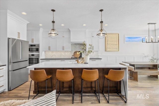 8701 W Suttle Lake Dr, Boise, ID 83714 - kitchen featuring stainless steel appliances, white cabinets, tasteful backsplash, a kitchen bar, and recessed lighting