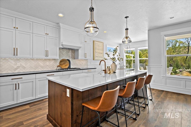 8701 W Suttle Lake Dr, Boise, ID 83714 - kitchen with stainless steel gas cooktop, decorative backsplash, dark wood-type flooring, a kitchen bar, and recessed lighting