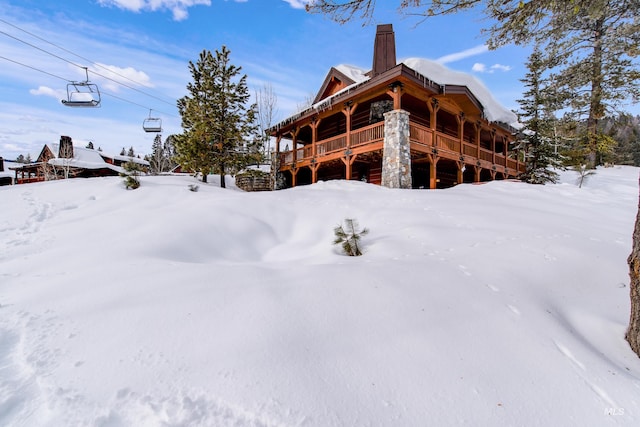 snow covered rear of property featuring a chimney