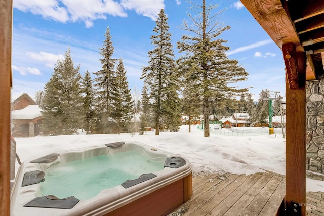 snowy yard featuring a deck and a hot tub