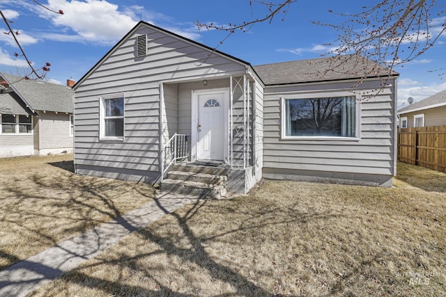 bungalow-style home with a front yard and fence