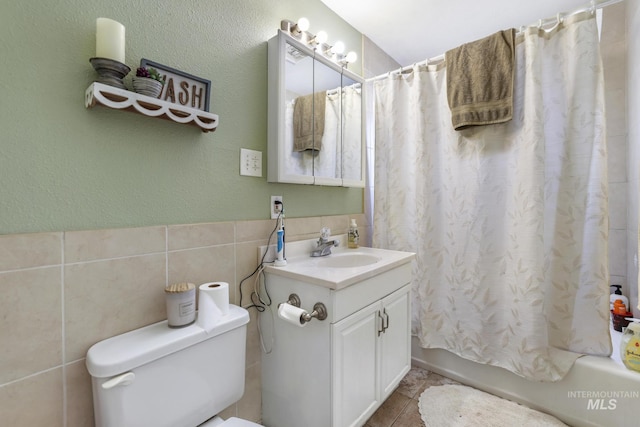 bathroom with toilet, tile walls, shower / bath combination with curtain, vanity, and a textured wall