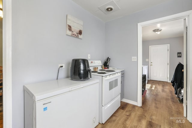 kitchen with light wood-type flooring, white range with electric cooktop, white cabinets, light countertops, and baseboards