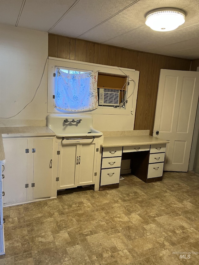 unfurnished office with cooling unit, sink, and wood walls