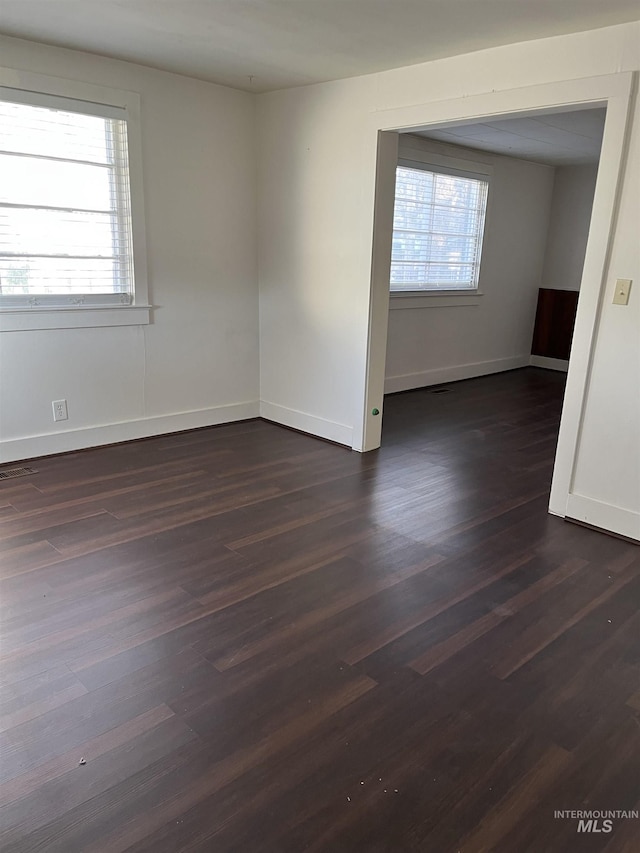 empty room featuring a healthy amount of sunlight and dark wood-type flooring