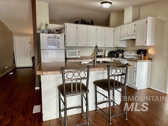 kitchen featuring sink, white cabinetry, dark hardwood / wood-style floors, and white appliances