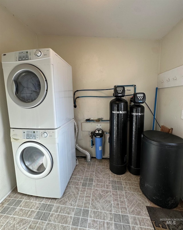 clothes washing area with stacked washing maching and dryer