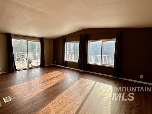 spare room with wood-type flooring and vaulted ceiling