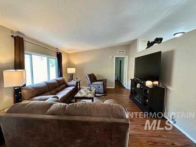 living room featuring dark wood-type flooring and vaulted ceiling